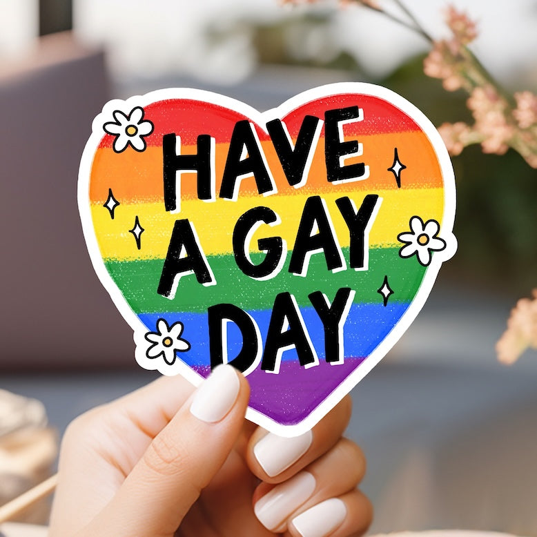 a person holding a heart shaped sticker that says have a gay day