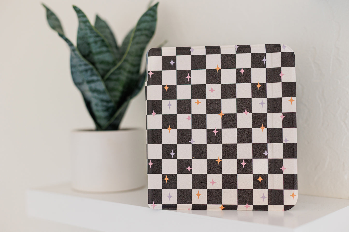 a white shelf with a potted plant and a black and white checkered patterned object, which appears to be a small decorative item.