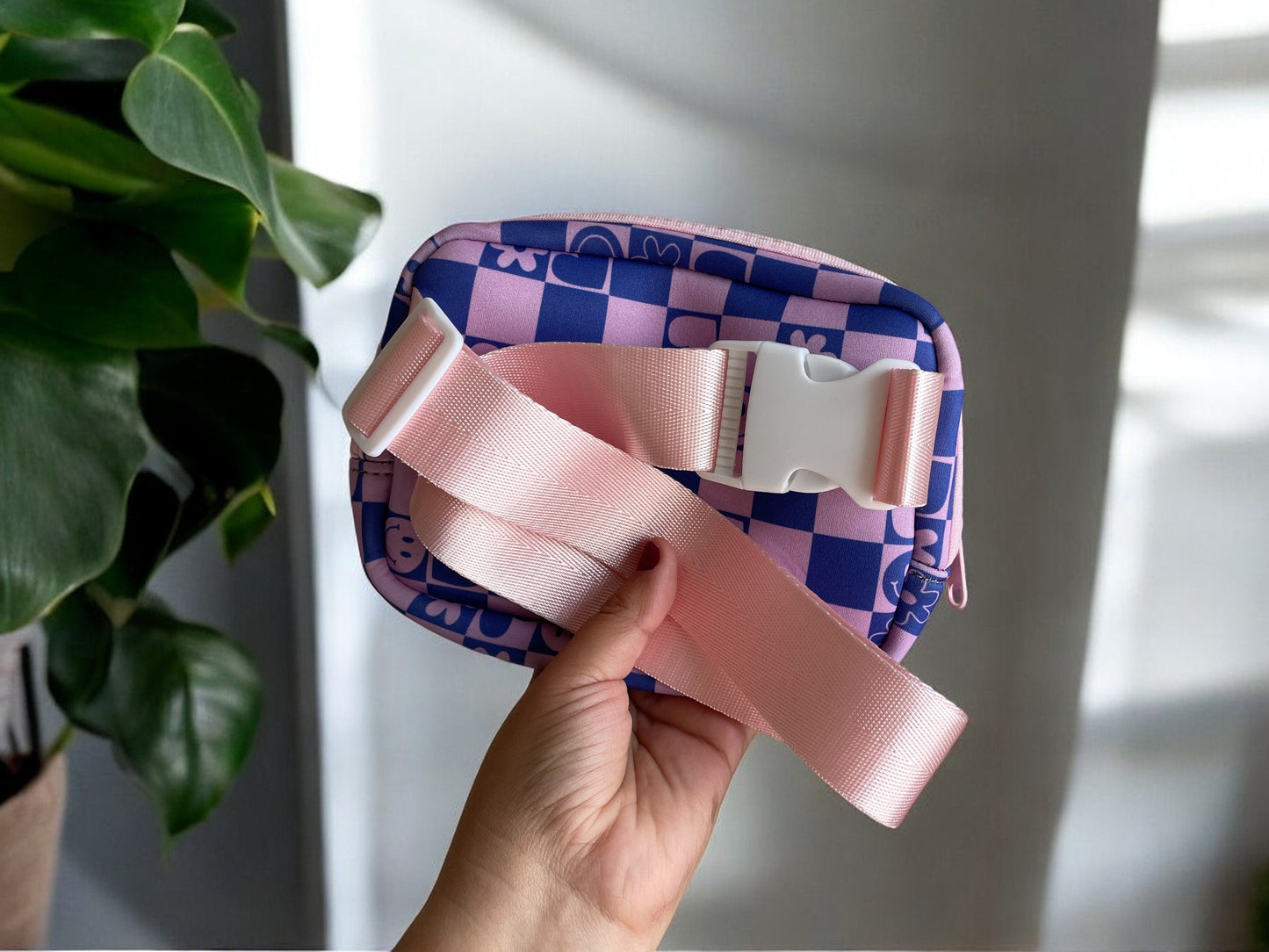 Checkered pattern nylon belt bag with pink strap and white buckles.