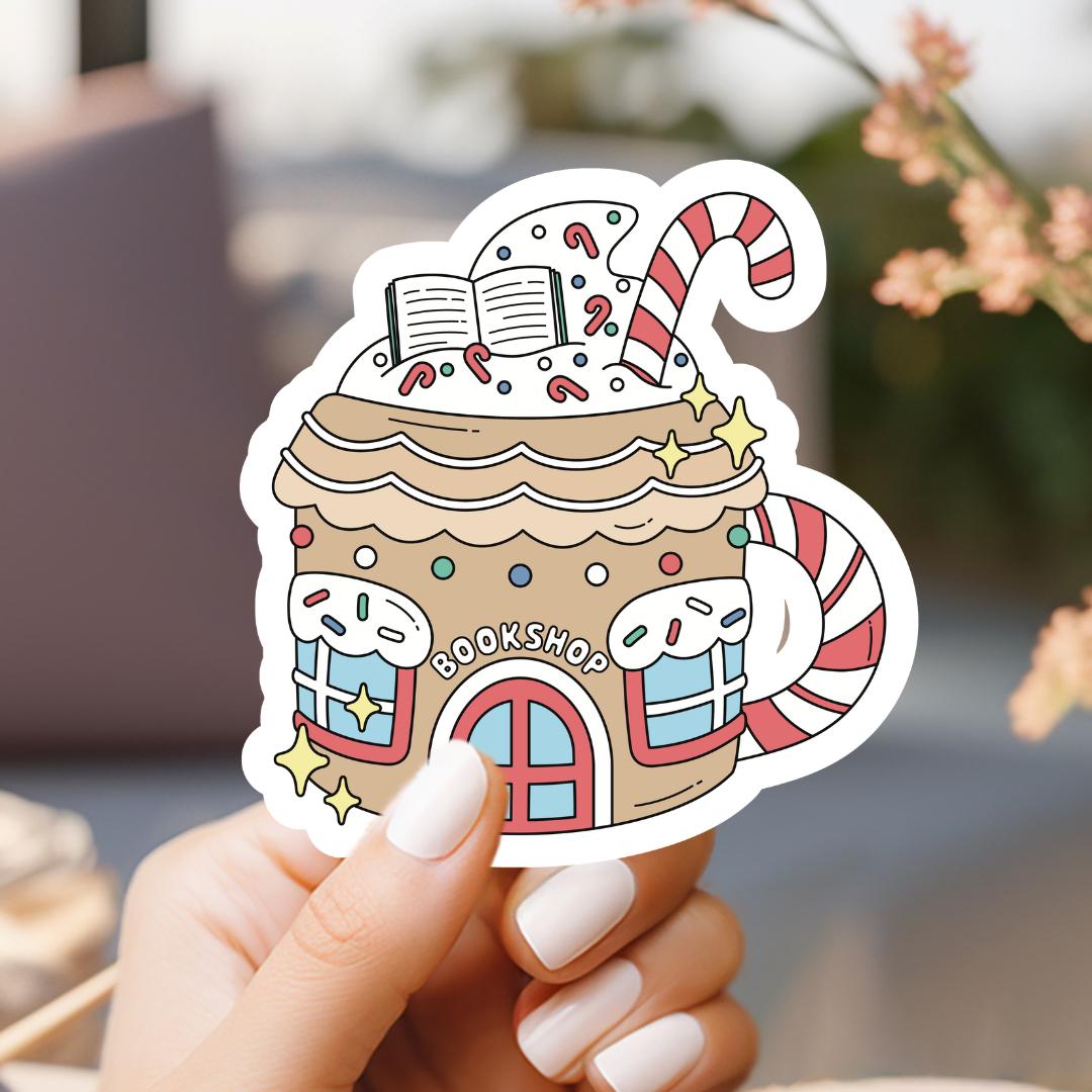 a hand holding a sticker of a gingerbread house