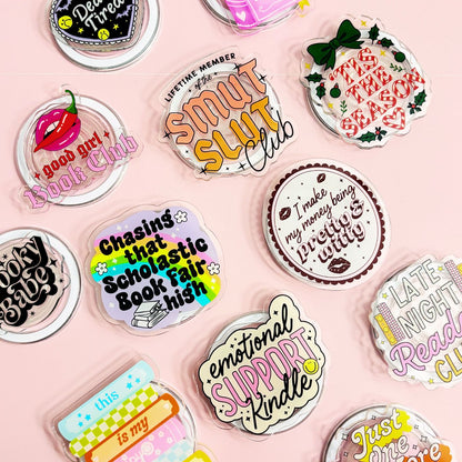 a collection of colorful stickers or magnets with various texts and designs, including phrases and logos related to clubs, books, and personal interests.