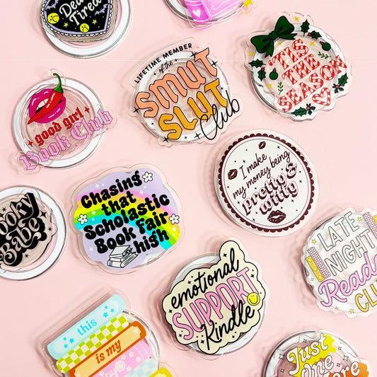a collection of colorful stickers or magnets with various texts and designs, including phrases and logos related to clubs, books, and personal interests.