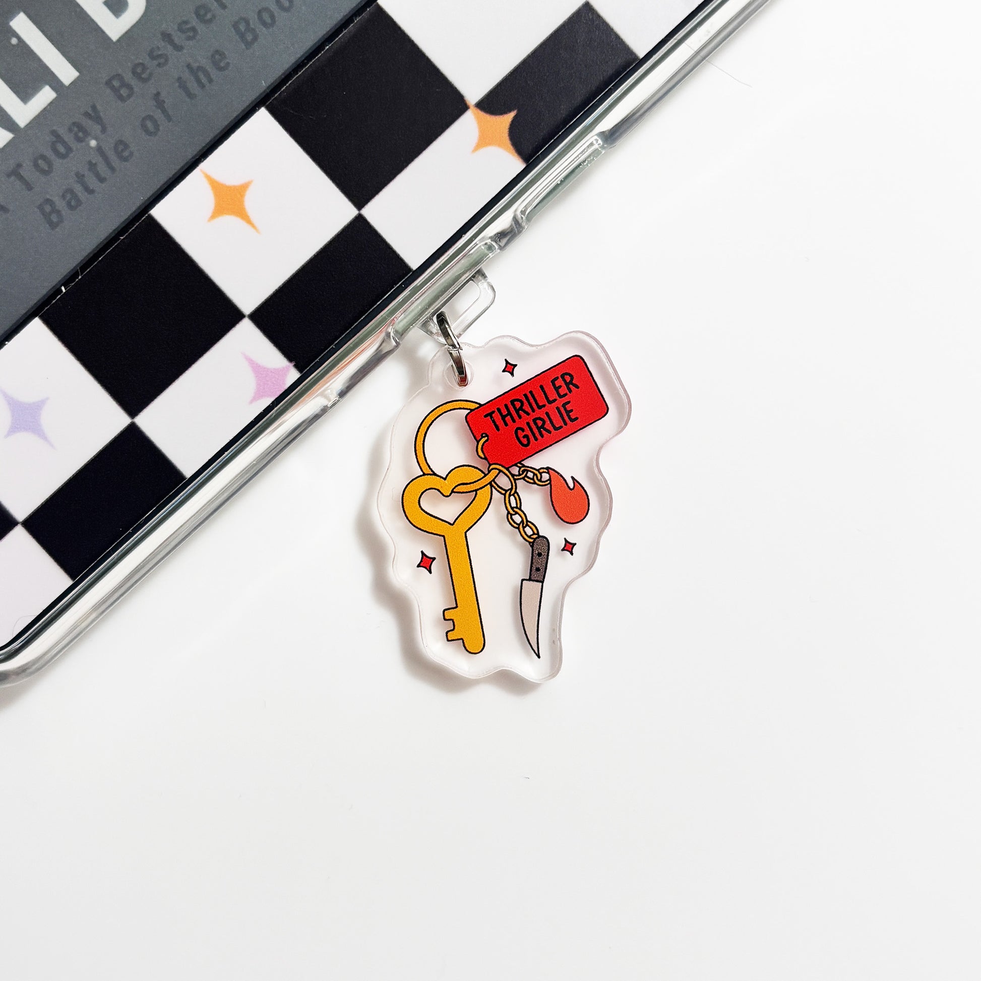 A clear plastic charm with a yellow key and a red heart-shaped tag attached to it, placed on a white surface.