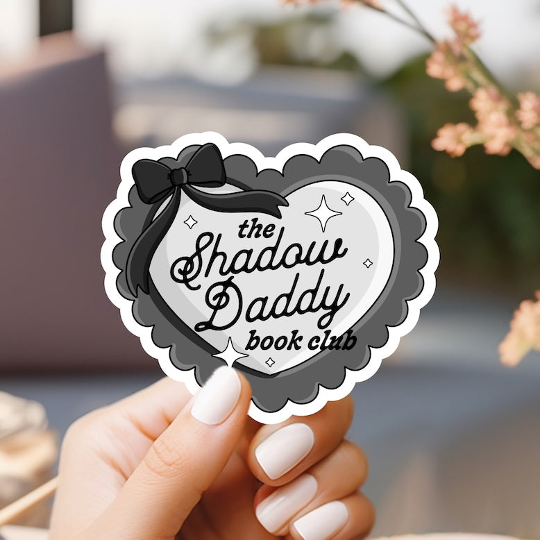 a person holding a sticker that says the shadow daddy book club