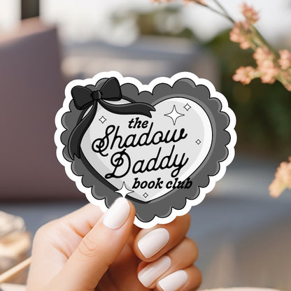 a person holding a sticker that says the shadow daddy book club