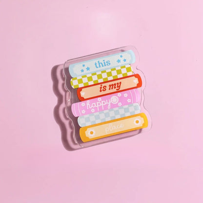 A clear plastic object with colorful bandages and text on it, placed on a pink background.