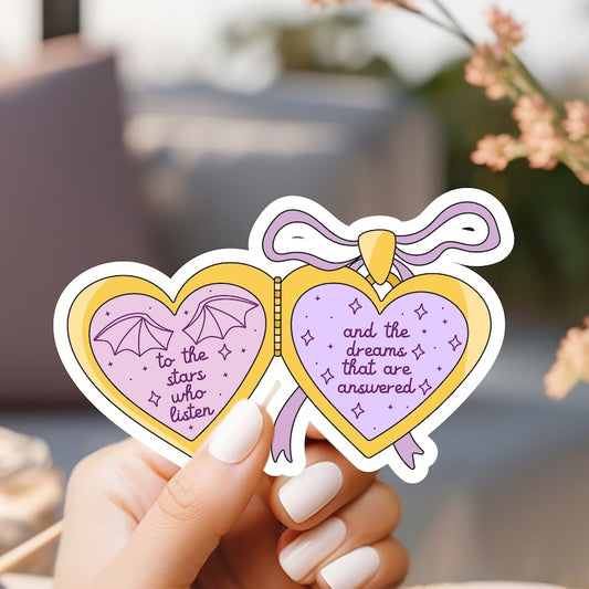 a hand holding a pair of heart shaped stickers