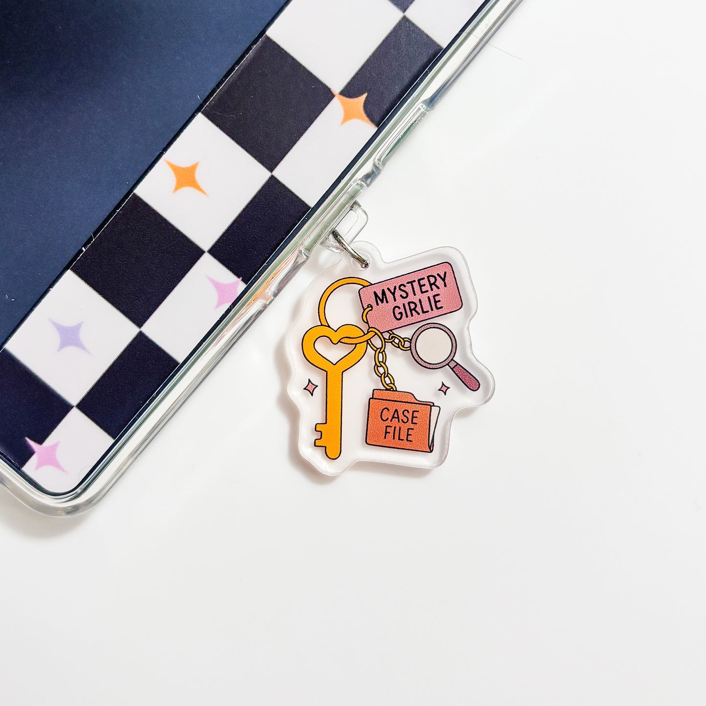 a clear plastic charm with a key and a magnifying glass, along with the text "Mystery Girl" and "Case File".