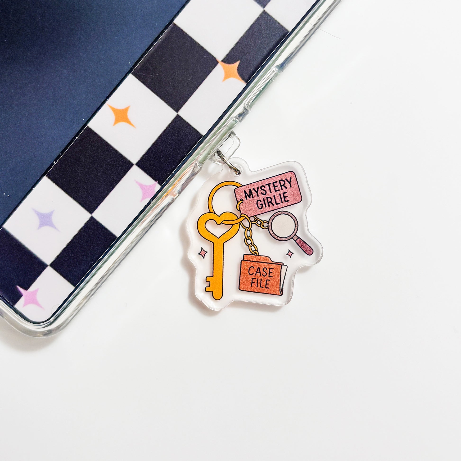 a clear plastic charm with a key and a magnifying glass, along with the text "Mystery Girl" and "Case File".
