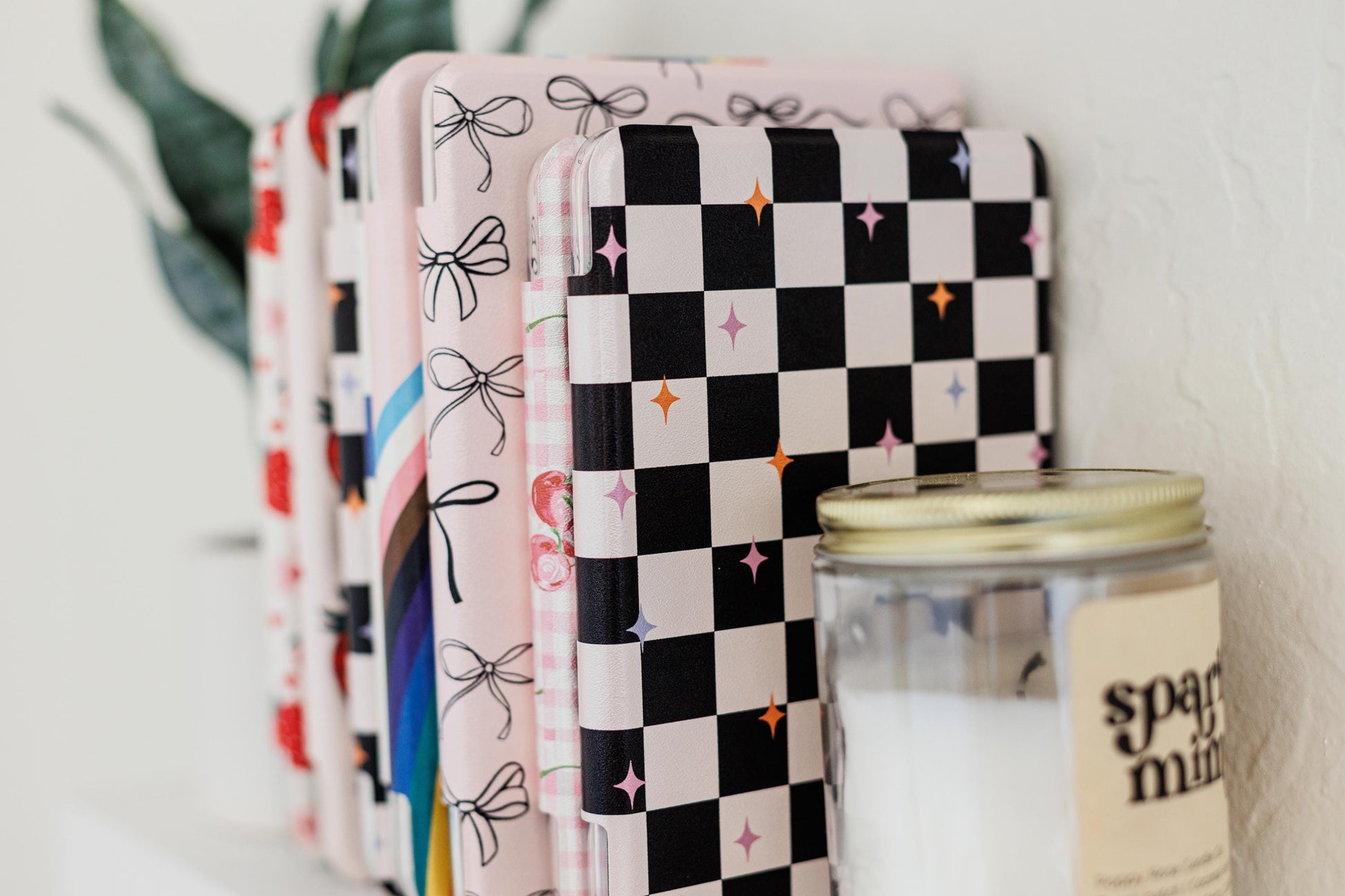 a collection of colorful notebooks and a candle on a shelf.