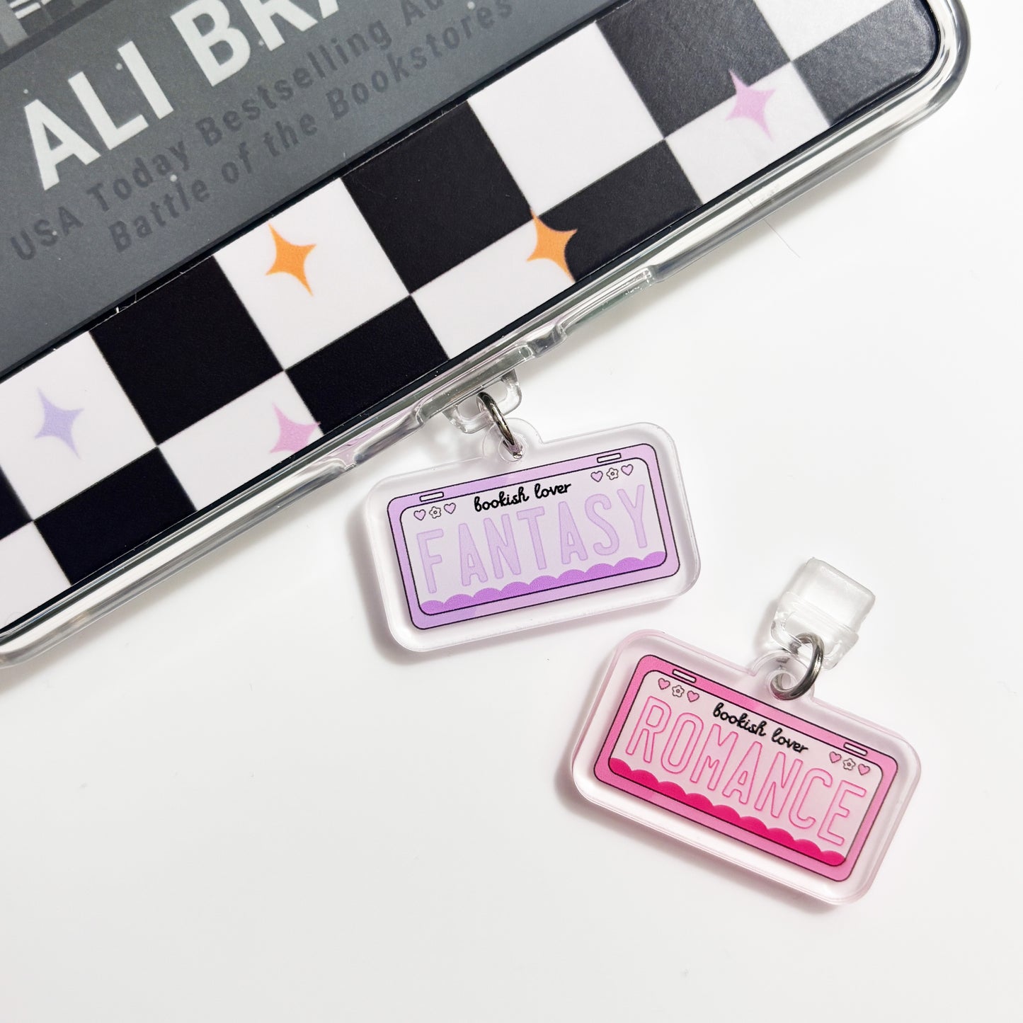 two clear acrylic charms hanging from a surface, each with a different word written on it.
