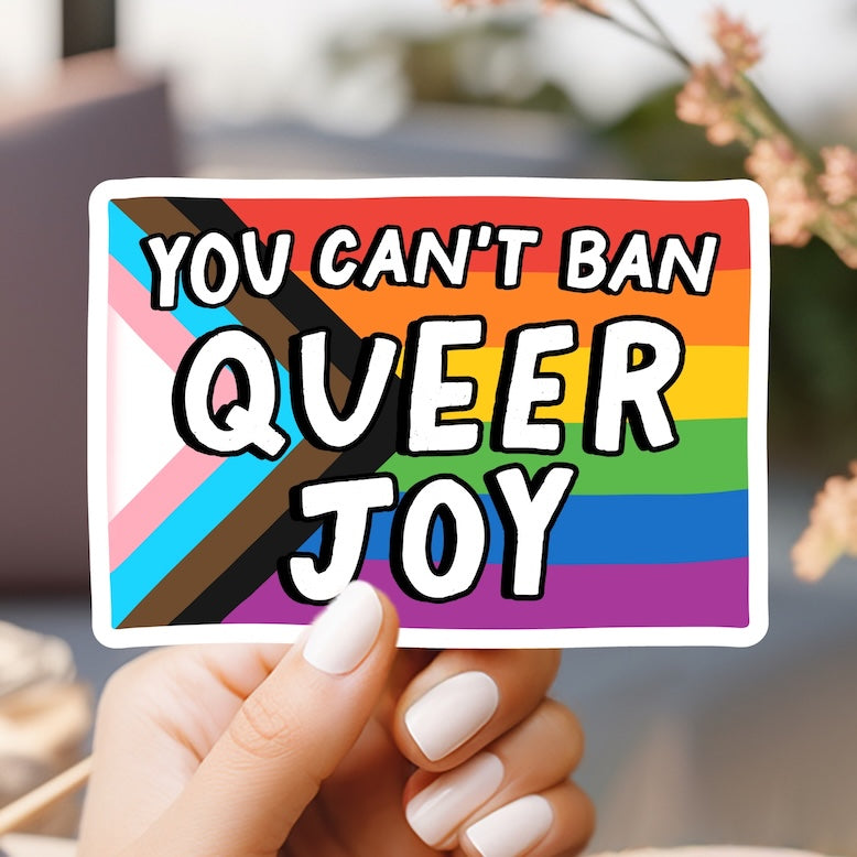 a person holding up a sticker that says you can't ban queen joy