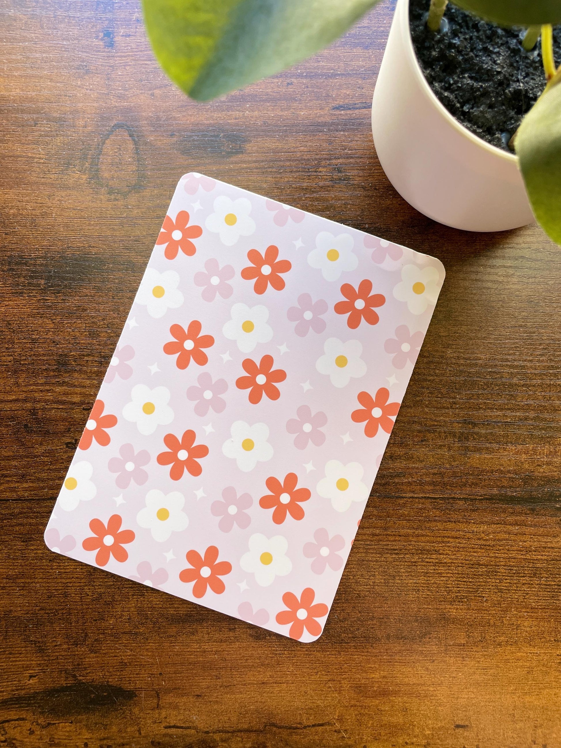 a potted plant sitting next to a pink and orange flowered notebook